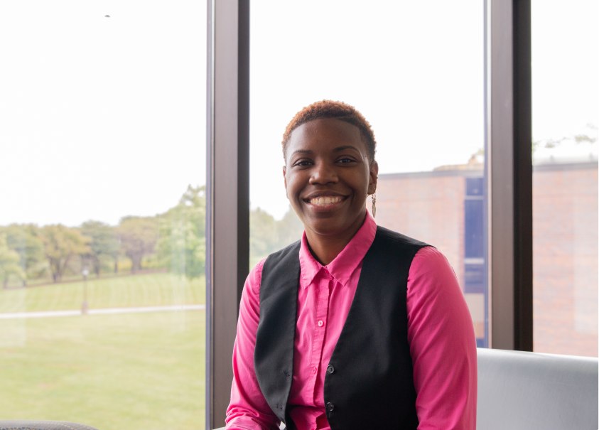 Nekia Driver, a GSU alumni, sitting in front of a window in the GSU building and smiling