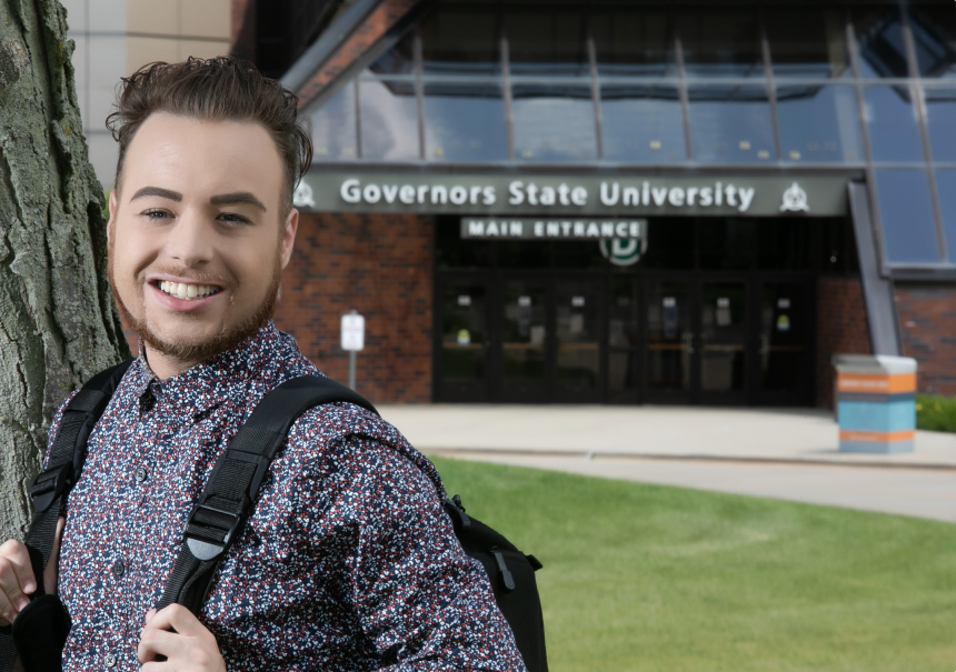 Peter Brassea, a GSU alumni, standing outside the main entrance of the GSU building carrying a backpack