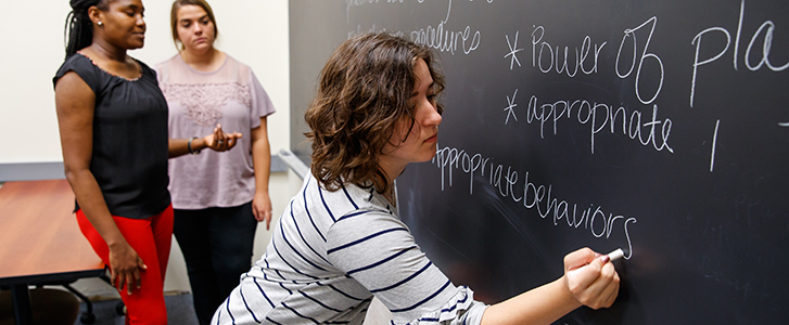 Student writing on chalkboard