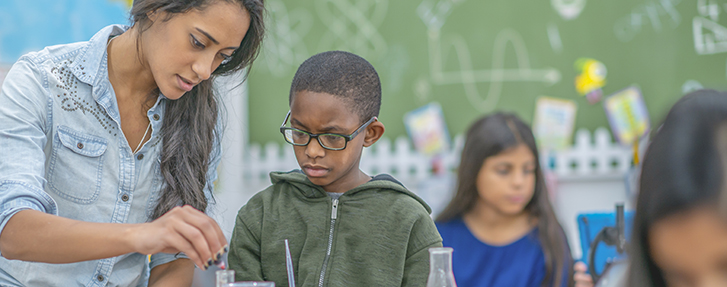 Teacher assisting student with chemistry experiment Teacher assisting student with chemistry experiment