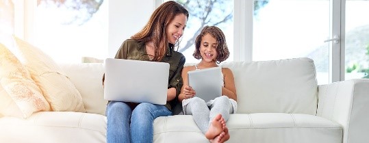 woman and daughter with laptop, sitting on sofa