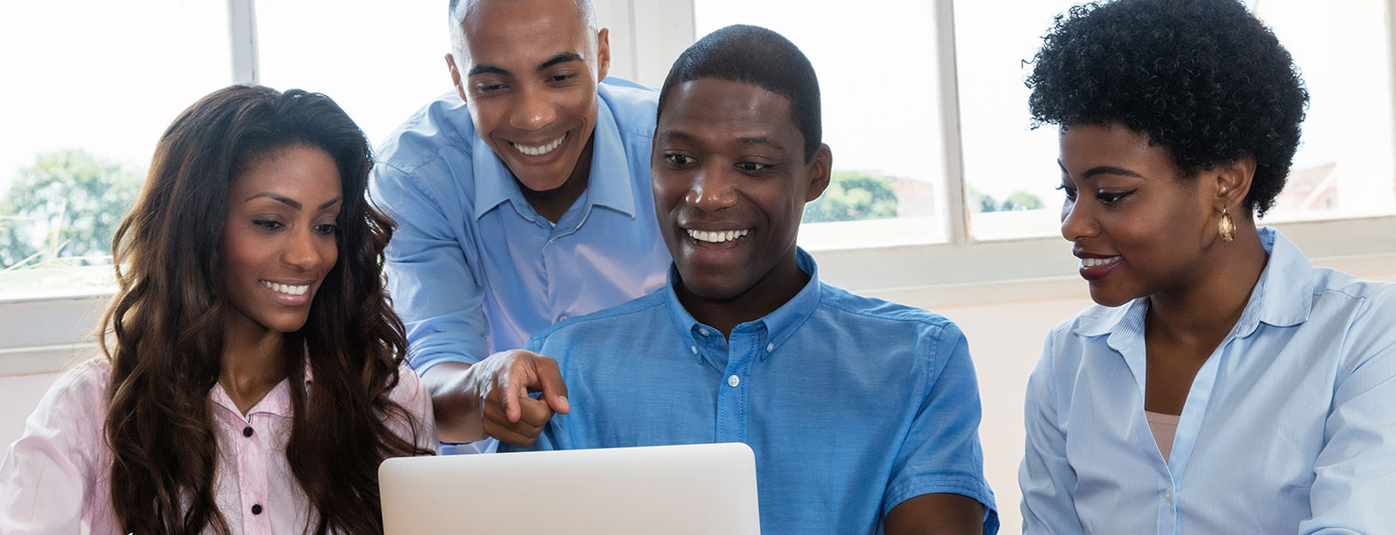 Smiling students pointing and looking at laptop screen