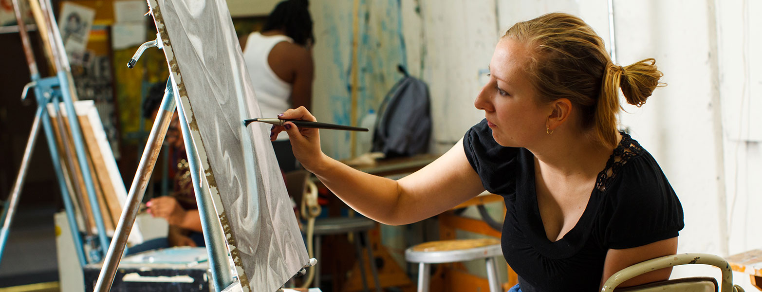 Female painting in art studio with other painter in background