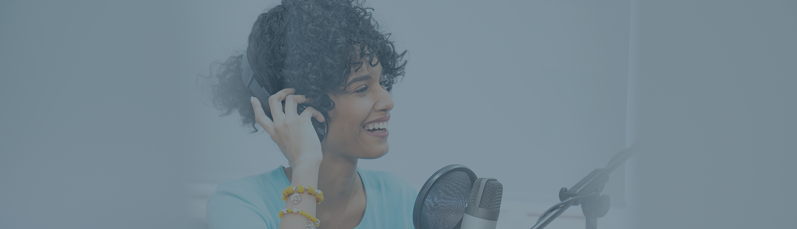 Person smiling wearing headphones near a microphone