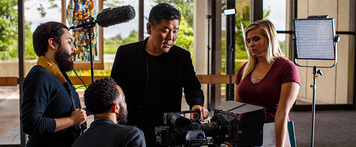 Professor showing students how to work film camera Professor showing students how to work film camera