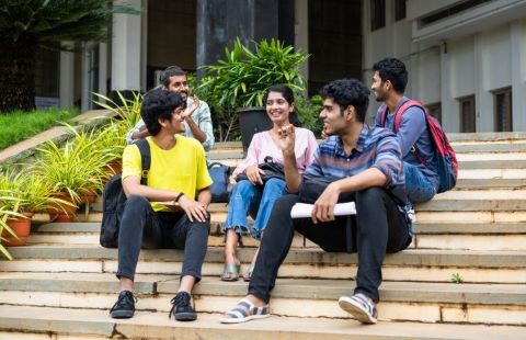 Students sitting on stairs outside of campus