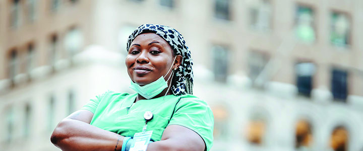 healthcare worker in scrubs with arms crossed in front of hospital healthcare worker in scrubs with arms crossed in front of hospital