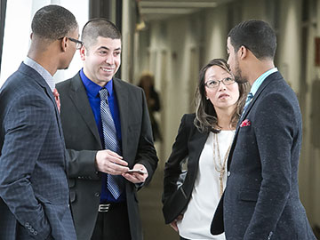 four businesspeople talking in a hallway