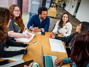 Students talking at a table in the hallway