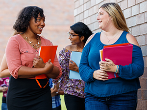 Students walking and talking while holding notebooks