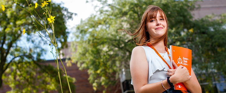 Student holding notebook outside