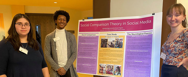 Students smiling next to their presentation poster board on Social Comparison Theory in Social Media