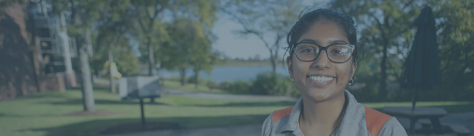 Student ambassador smiling and standing outside by pond
