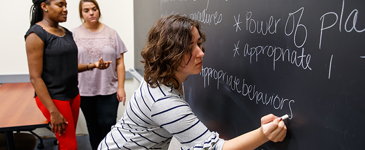 Students writing on chalkboard