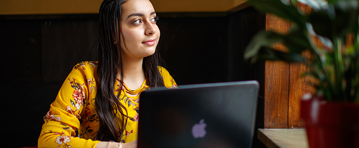 Student with laptop looking out window