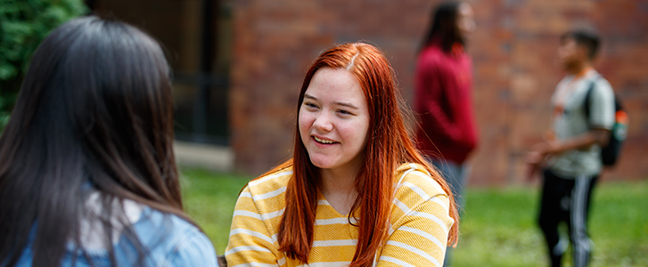 Students talking outside on bench