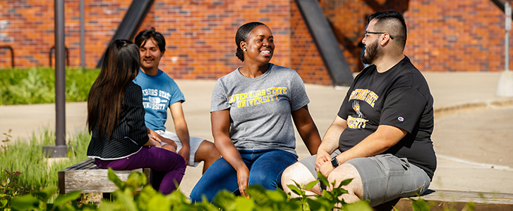 Students talking outside on bench