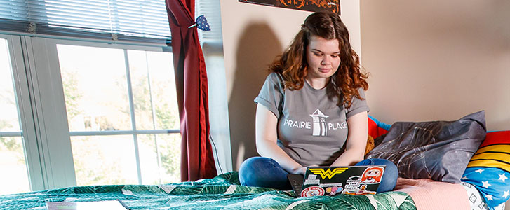 Student using laptop while sitting on bed. Student using laptop while sitting on bed.