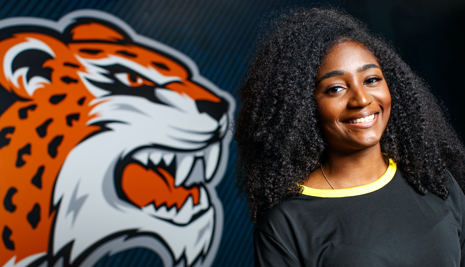 Student smiling next to GSU Jaguar wall print