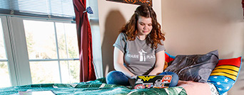 Student sitting on bed using laptop