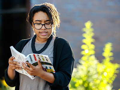 student reading from book outdoors