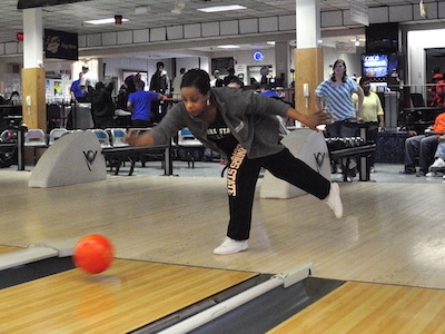 Student throwing bowling ball down lane