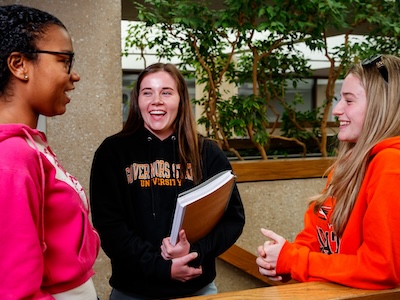 Students holding books and talking in hallway