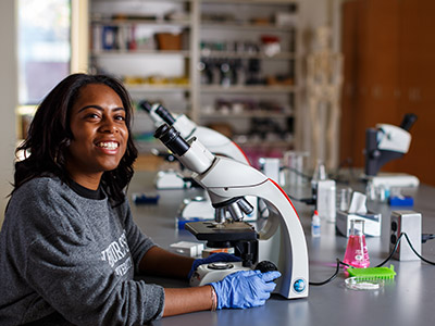 student with microscope in lab