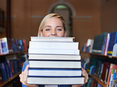 student behind stack of textbooks