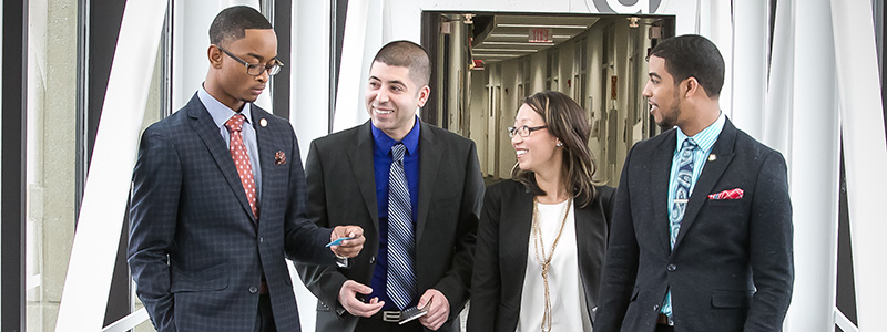 four business students on the bridge to the G Building