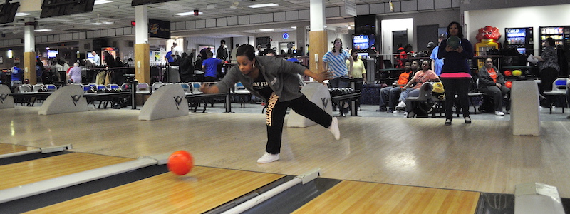 Student throwing bowling ball down lane
