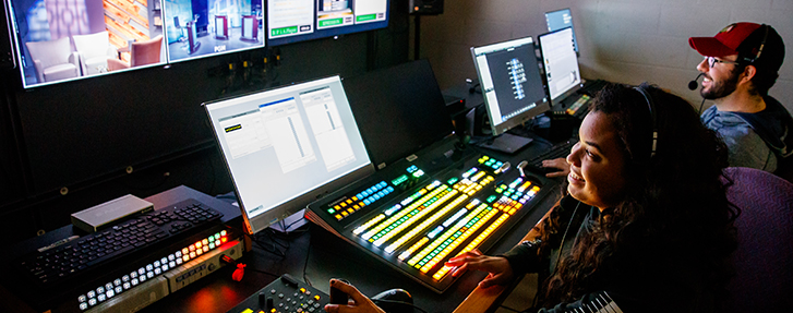 People looking at computer and TV screens in a studio
