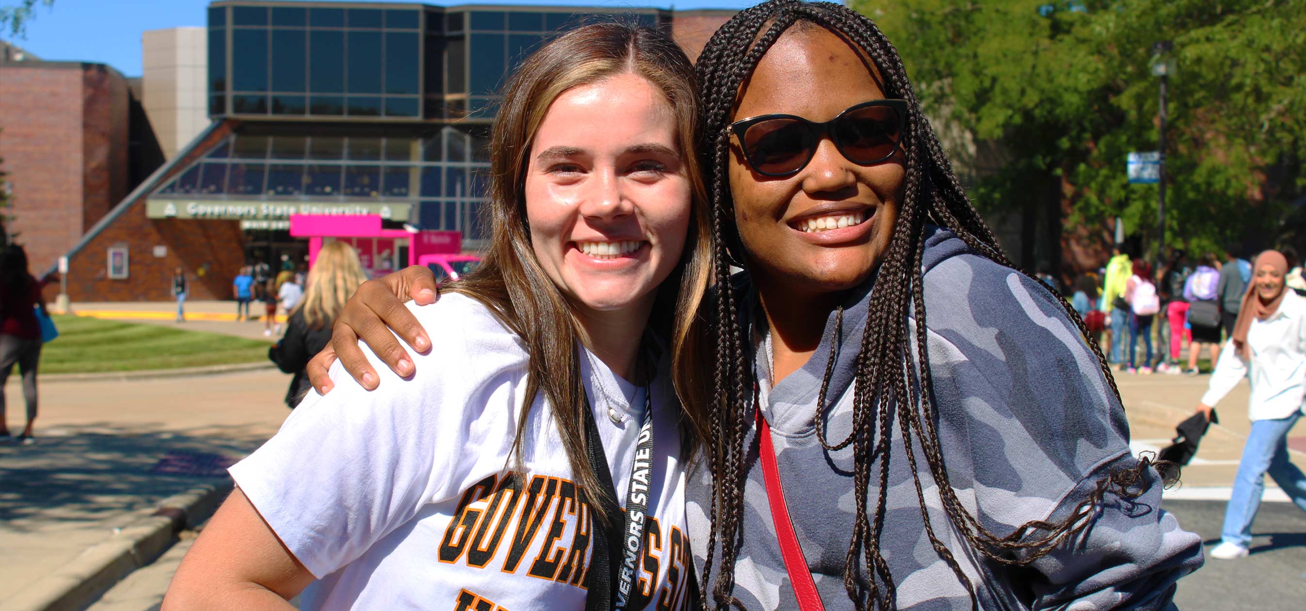 Students smiling outside campus entrance