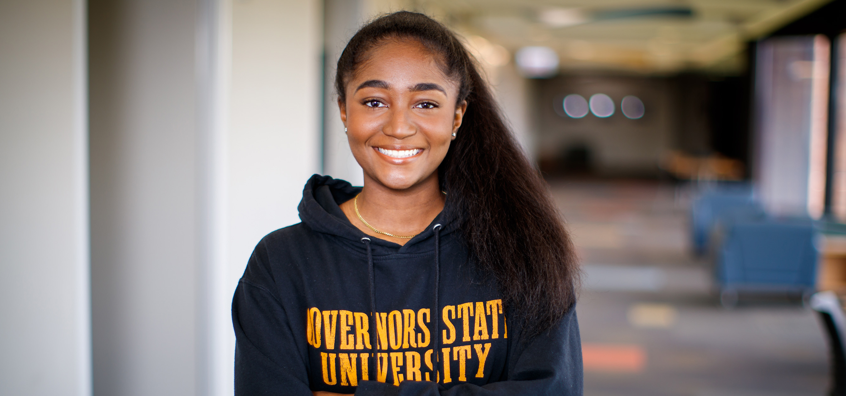 Student wearing Governors State hoodie standing in campus hallway