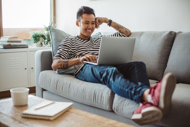 Student relaxing on couch and looking at laptop