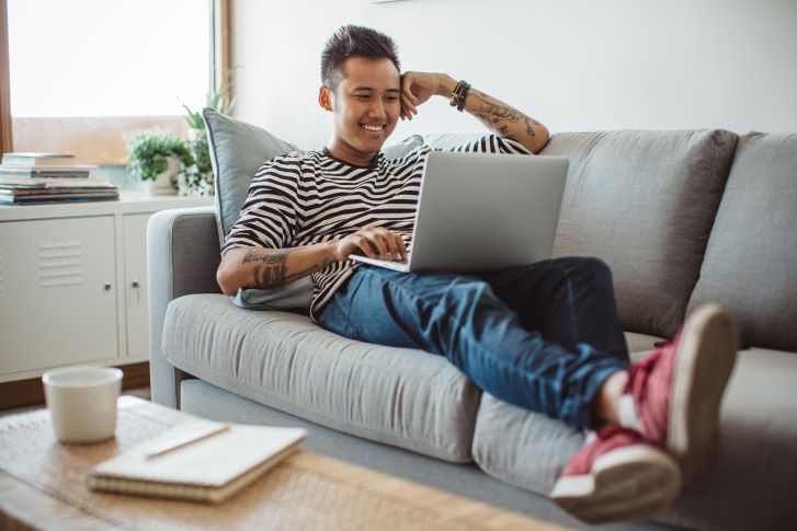 Student relaxing on couch and looking at laptop Student relaxing on couch and looking at laptop