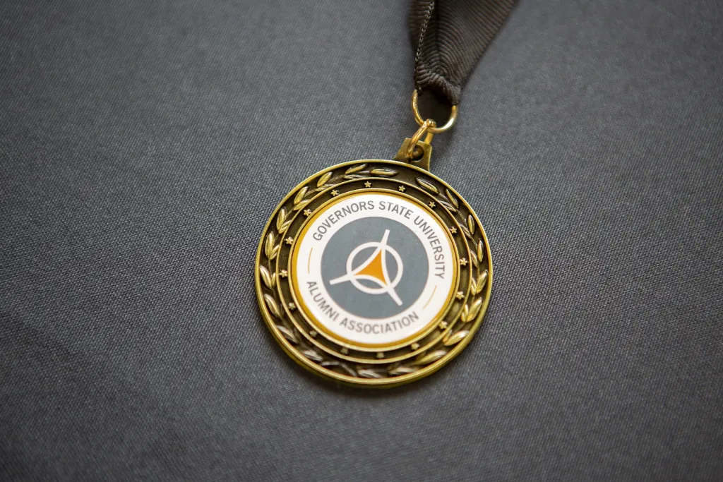 Gold medal with a laurel wreath edge and Governor's State University Alumni Association logo.