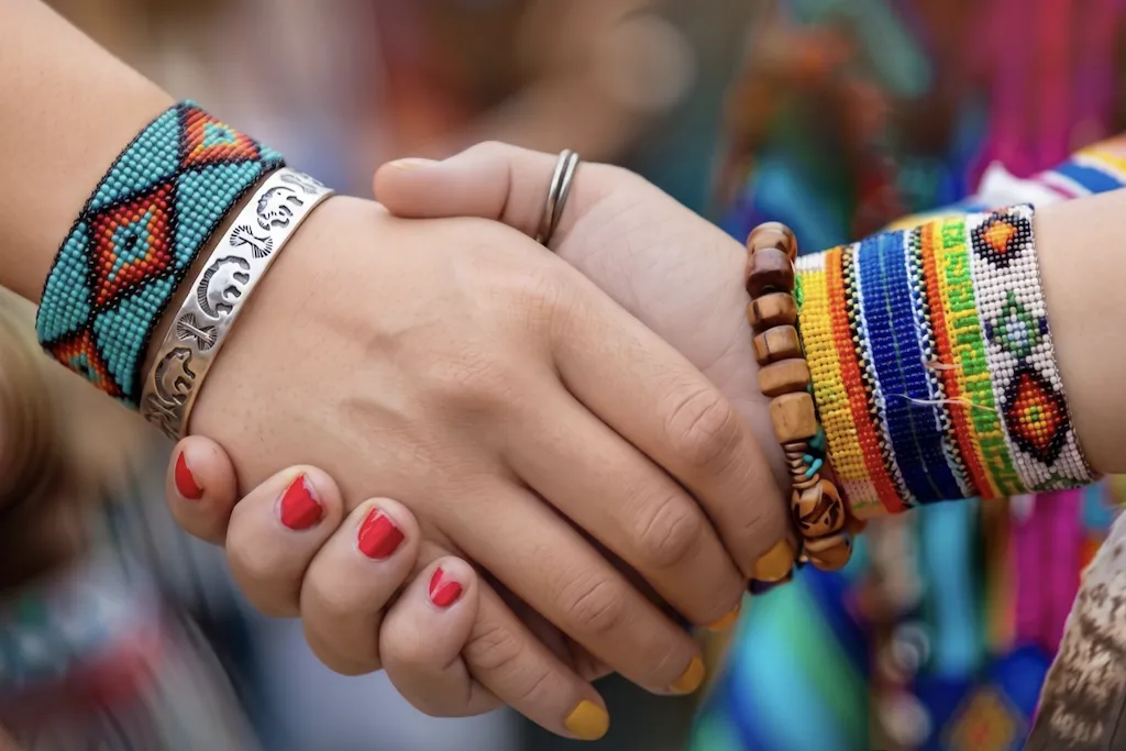 Shaking hands with colorful beaded bracelets and painted nails.
