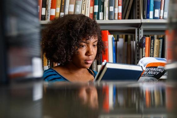 Student standing between bookshelves at the library