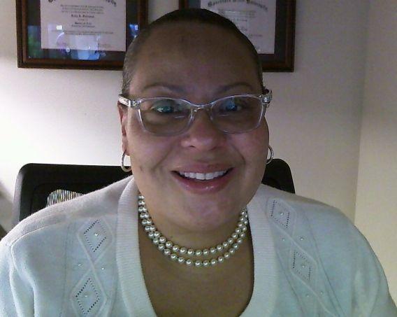 Photo of woman wearing glasses, pearl necklace and white sweater