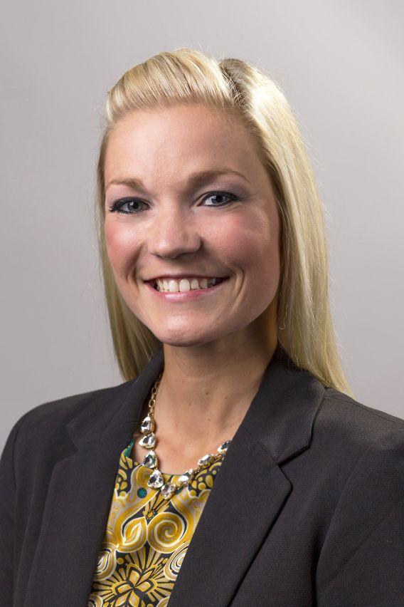Professional photo of woman with long blond hair, wearing dark blazer and patterned blouse