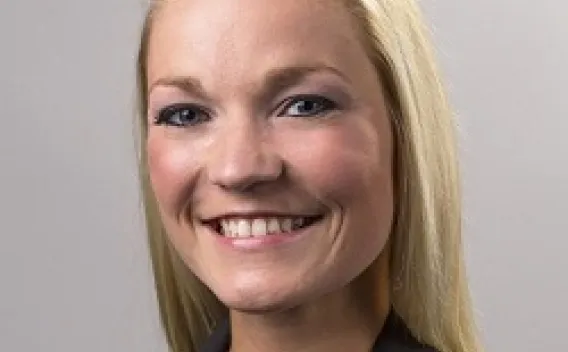 Professional headshot of woman with long blonde hair, wearing a dark suit