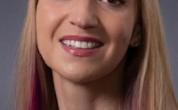 Woman with blonde hair, brightly colored shirt. 