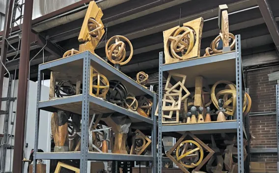 Two shelves filled with numerous intricate wooden geometric sculptures.