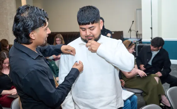 Pinning ceremony Man in black adjusts a pin on another man's white shirt.