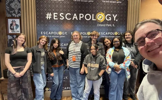 Diverse group of young people smiling in front of an Escapology banner.