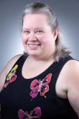 Smiling woman with graying hair in a black top with colorful butterflies.