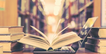 Open book on top of laptop in library